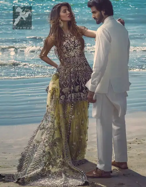 Charade net peplum having halter neckline. Peplum adorned with light golden, pearls and mix embellishment. Husk net sharara and dupatta.