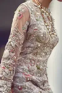 Ivory white long fitted bridal maxi. Maxi adorned with colorful embellishment using appliques and threads. Bridal maxi comes with two tones dupatta having peach and ivory white shades.