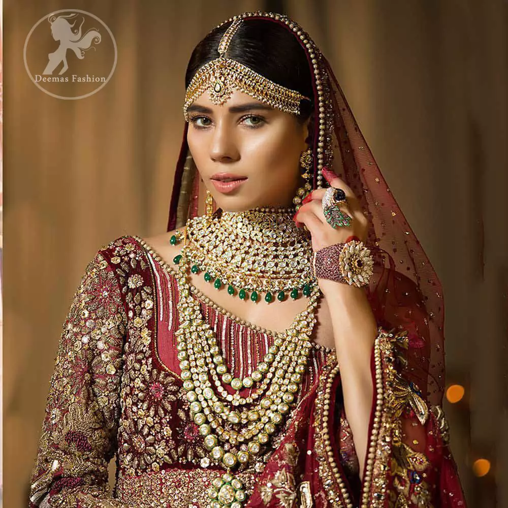 This maroon angrakha frock heavily embellished in the front with silver gold kora dabka, kundan and stones work. One side shoulder neckline is beautifully ornamented with sequins lines in geometric manner. Paired up with matching brocade sharara which looks so magnificent. This outfit is meticulously coordinated with maroon dupatta with embellished borders on lengths.