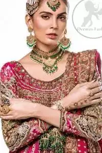 This bridal dress is adorned with floral embroidery.It is meticulously highlighted with dull golden and antique shaded kora, dabka, tilla, sequins and pearls. It has beautiful embellished bodice and U-shaped neckline which adds to the look.Sleeves are embellished with embroidered applique. Hemline is adorned with beautiful tassels. It is artistically coordinated with brocade embellished gharara. Gharara is allured with beautiful contrast of rust and plum color. It comes with pink dupatta which is decorated with embroidered borders and sprinkled sequins all over.