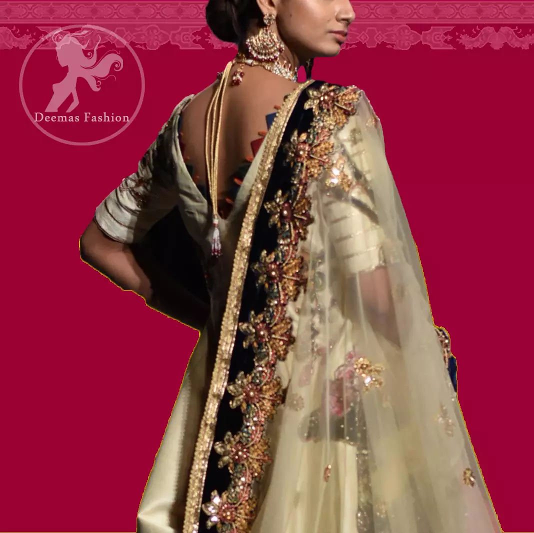 This signature angrakha is crafted with raw silk featuring hand embroidery with elegant zardoze work. The sharara with it is made of brocade with applique detail on bottom done with kora dabka, kundan and tilla work. It comes with ivory dupatta adorned with black applique and heavy embellished borders on all sides.