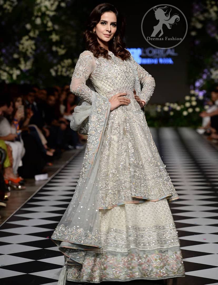 Feel glamorous in our ivory back trail frock with fascinating embellishment on neckline with silver kora, dabka, pearl and sequins. The detailed embellishment at the daaman instantly draws attention. It comes with an exquisite lehenga with thick embroidered borders to give it a regal look. The outfit is finished by beautiful applique embellished lehenga. It is coordinated with tissue dupatta which is sprinkled with sequins all over it. It is further furnished with four sided embellished border.