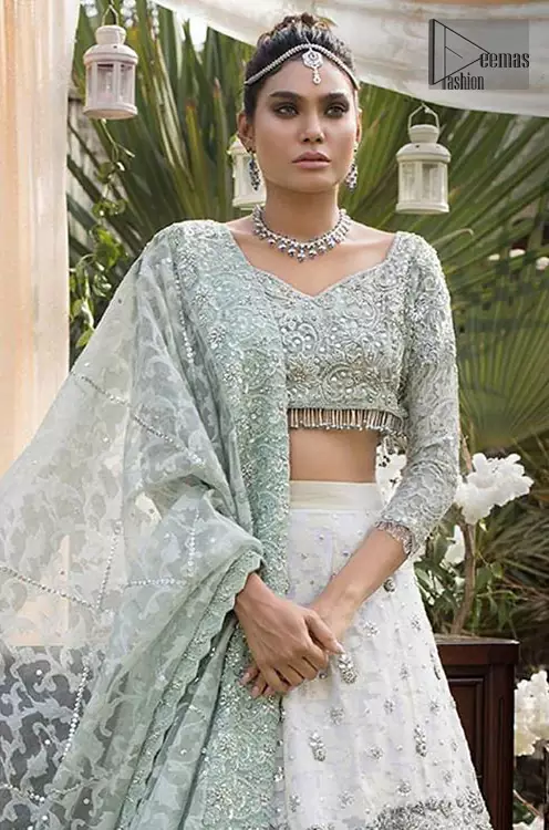 This bridal dress is perfect for your wedding or nikah day. Create a vision of elegance with this ivory self printed lehenga decorated with intricate zardosi detailing and silver kora, dabka and sequins. Furthermore it is adorned with scattered tiny floral motifs. Having quarter sleeves adorned with motifs. Beautifully coordinated with heavy embellished blouse with silver kora, dabka, sequins and pearls all over and finishing with tassels at the end. It comprises with light green self printed dupatta having matha patti border on the front and intricate beautiful border on all rest of the three sides.