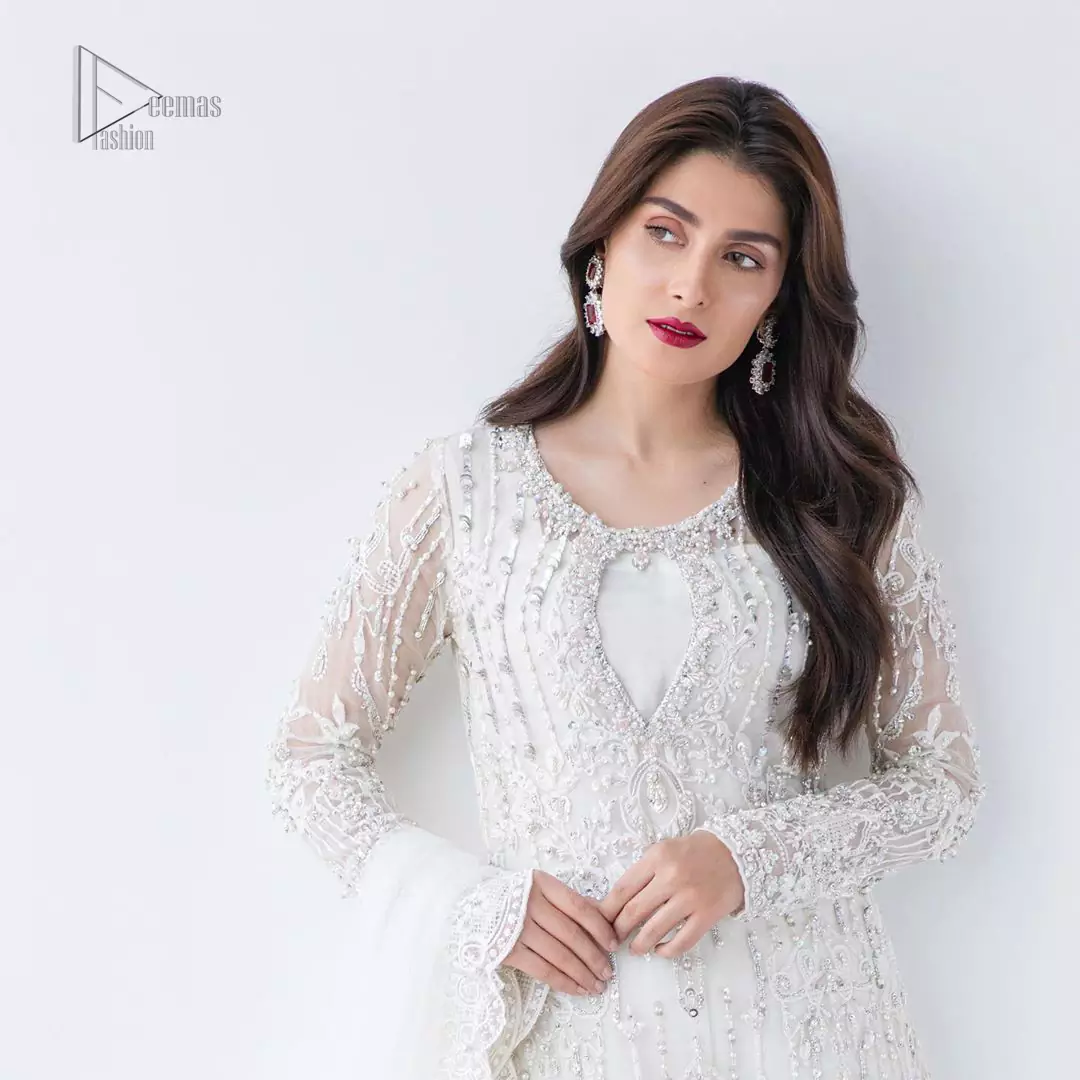 This is an ensemble that deserves to be flaunted. The ivory white shirt is an example of remarkable handiwork. With a lot of attention to detail, the intricate sequencing using glass beading and threads makes the shirt look like nothing but a dream. Furthermore the shirt is enhanced with thick embellished scalloped hemline. Sharara is magnificently decorated with scattered crystals all over. Beautifully paired it up with ivory white dupatta having four sided scalloped border.