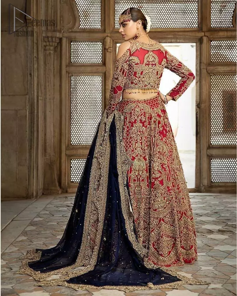 A breathtaking red traditional lehenga  paired with a detailed blouse, equally alluring make for an ensemble which is comfortably chic. The blouse is done with golden and antique shaded embroidery and finishing with tassels. Blouse having cold shoulder full sleeves. The lehenga is enhancing with the art of classical heritage showcasing the craftsmanship of kora, dabka, tilla, kundan and sequins detailed, artistically embellished to give a beautiful rhythm to the outfit. It comprises with navy blue dupatta sprinkled with sequins and four sided scalloped border. This is an ensemble that is sure to invite compliments galore.