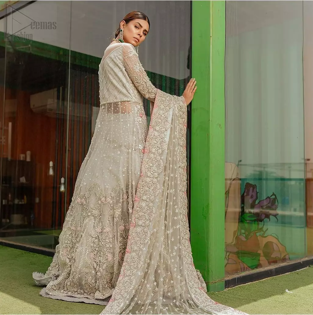 This garnet ensemble is sure to make you look like glamorous royalty with immaculate work covering every inch of the maxi. With a flowing train, this is an ensemble that deserves to be flaunted. The maxi is crafted artfully with silver zardozi work and multiple color thread embroidery. The bodice is heavily decorated with silver kora, dabka and tilla work. Furthermore, scattered sequins all over to give it a perfect look. Balance the look with light gray lehenga adorned with frilled bottom. Dupatta is decorated with vintage floral on pallus and finished with embroidered border on four sides which makes this outfit more beautiful.