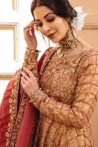 Chic and sophisticated perfectly describe this simply stunning wedding dress. This artisan piece includes intricate hand embellishment. This technique gives our garments a unique look, and helps to sustain a traditional craft carried out by skilled artisans across Asia. The short frock is fully embellished with zardozi work in the shades of golden and silver on tea rose canvas. Finished with dangling pearls on hemline. Compliment the look with coral back train lehenga exaggerated with embellished bottom and sprinkled floral bunches. The coral raw silk dupatta is emphasized with intricate embroidered borders.