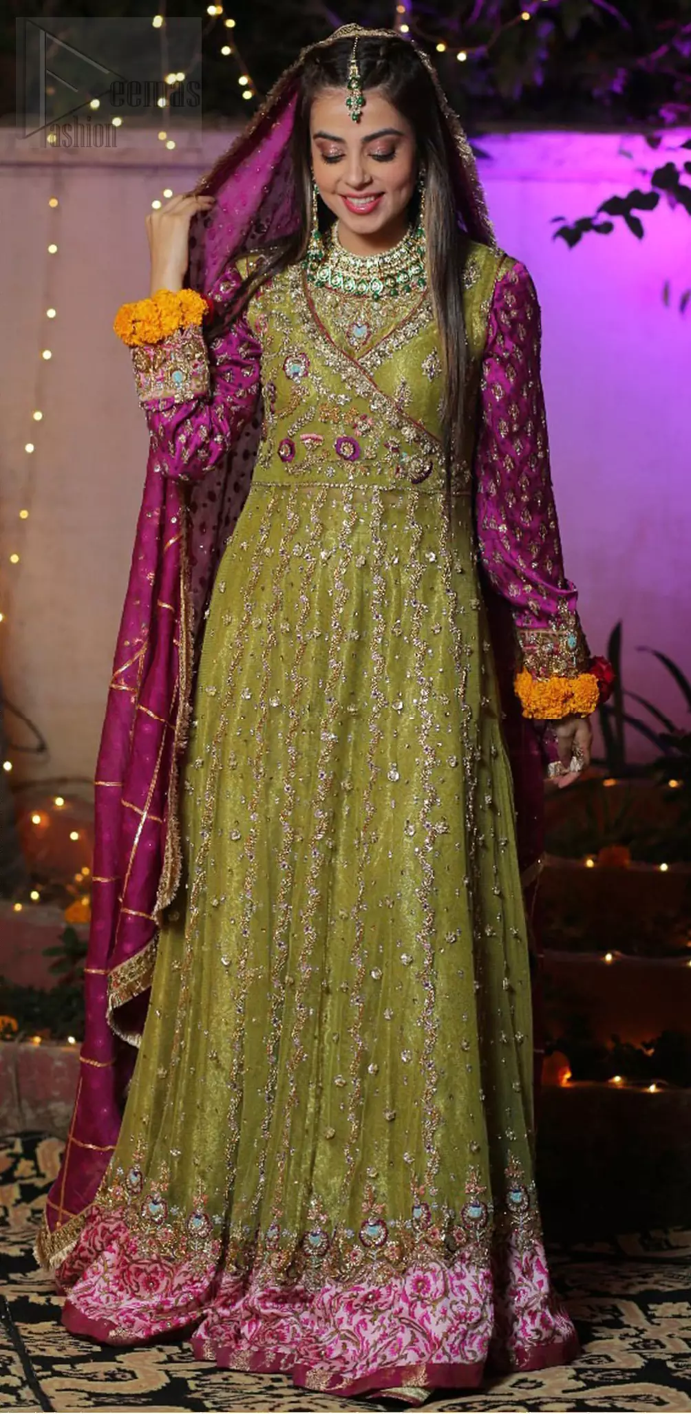 Nothing speaks of femininity and class louder than this mehndi outfits for bridesmaids. The sequinned whimsical florals embroidered across the flattering bodice in this ethereal frock is sure to turn heads in every room you walk into. The pairing of champagne zardozi work with parrot green fabric is an artist’s dream colour palette. The frock hemline is emphasized with banarsi applique details that gives perfect ending to this outfit. It comprises with matching tissue lehenga. The magenta organza dupatta with chann and gota work, finishing with kiran lace all around the edges makes the look complete. 