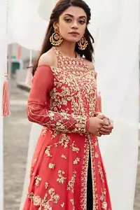 This outfit brings drama and playfulness to traditional frock and Sharara with a modern approach. Drape yourself to perfection for the classic affair in this flattering front open ensemble festooned with intricate zardozi hand embroidery work and motifs. The frock is furthermore adorned with halter neckline and comprises with overlaped bodice. Embellishment is done with zardozi embroidery in silver color. This outfit is comprises with bottle green velvet sharara and coral chiffon dupatta with sequins spray all over.