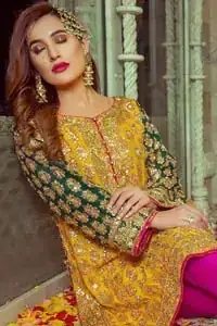 Embrace the season of festivities with this beautiful dress. This beautiful mehndi dress comes with a pink capri pants with beautiful embellished applique around the bottom and the shirt is designed with vertically worked gold lines and it finished with a thick appliqued embellished border. The shirt looks more whimsical when it comes with embellished green sleeves with golden zardozi work. Balance the look with yellow organza dupatta scattered with sequins on the ground.