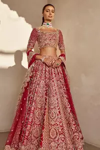It's all about looking stunning with a gorgeous Red Lehenga Blouse on your big day. Made with pure organza, this beautiful red dress is designed with trendy half sleeves, following a blouse choli styled exquisitely with a criss-cross pattern on sleeves. A boat-shaped neckline makes your beauty bones prominent while a marvellous touch of silver and golden embroidery, in addition to a few charming tassels, contributes to the magnificence of the dress. This highly appealing attire is surely going to get you a lot of praise on your Reception day.