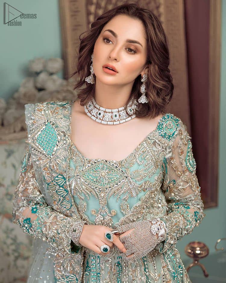 This style-savvy bride totally pulled off our classic bridal wear with unmatchable grace-giving major bridal goals. Featuring beautiful handwork, this outfit has a delicate arrangement of hand-embellished floral patterns with pearls and crystals along the length. Refined craftsmanship is at its best with hand embellished zardozi work elegantly all over the outfit. Frilled on the bottom of the maxi makes the outfit look like nothing but a dream. This outfit is paired with an organza dupatta with embroidered border and raw silk churidar pajama, making it a statement piece.