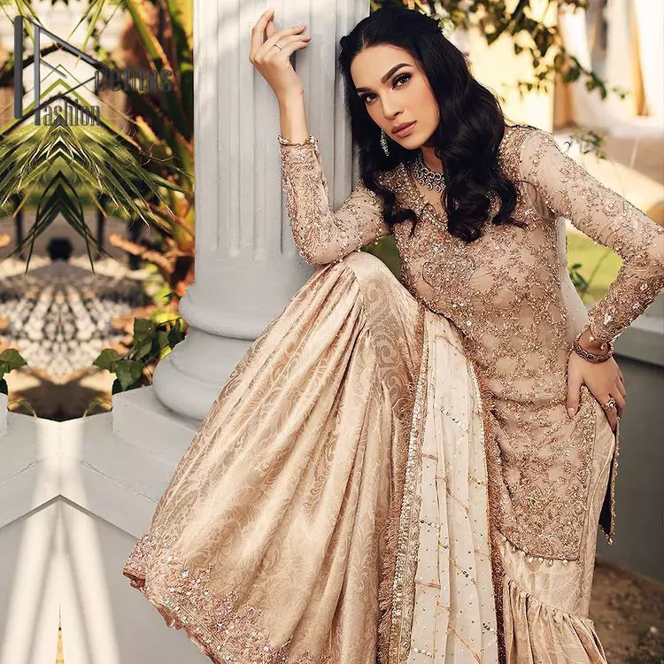Opt for a versatile outfit for your Nikkah that is the perfect amalgamation of splendid colours, deluxe fabrication, and exquisite profile as well. Satiate your soul with extraordinary ensembles from this fawn short shirt gharara of DeemasFashion outfits. The round neckline of the short shirt is just amazing when combine with full sleeves. Further, it is highlighted with antique embroidery that includes tilla, kora, and dabka work. Pair up it with fawn gharara made with pure Katan banarsi jamawar fabric just to grant you a super aesthetic look. Complete this outfit with a fawn dupatta that is embellished with a four-sided embellished border and kiran lace as well.