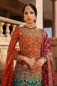 Be a happy and charming bride just like orange is a happy colour. DeemasFashion presents you with an orange short shit that is laboriously embellished with golden embroidery. The base of embroidery starts from the boat shape neckline of the shirt that giving a fully artistic look. In addition to this, it is enhanced with tilla, dabka, kora and Kundan work. The half sleeves of the dhirt also enhance the beauty of the handwork. It is coordinated with orange gharara that is perfect for entimate evening of your Mehandi. Finish this outfit with Pink dupatta that is adorned with ravishing details, the embellished borders represent the craftsmanship of DeemasFashion.