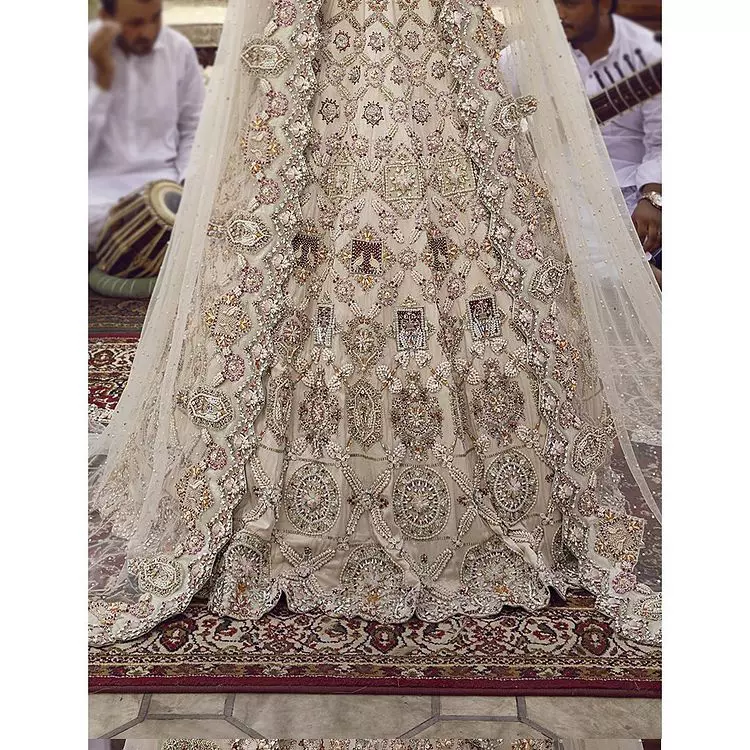This vibrant canvas is all your brides need to cheer in at your special Nikah moments. A beige white blouse has a V shape neckline and full sleeves embellished with golden and silver embroidery. It is further intensified with special tills, dabka, kora, Kundan and the magic of zardozi to make your day outstanding and more funable. It is paired up with embroidered scalloped lehenga to fulfil the dreamy fairy look of the bride. Complete this article with a scalloped dupatta in the same colour with a four-sided embellished border and sequins sprayed all over to cheer up.