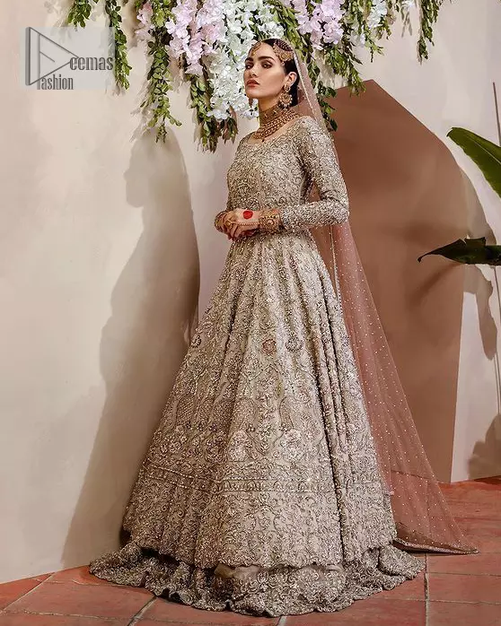 Walk with style on your Nikah day and let the flare follow! This light fawn flare maxi is decorated with tilla, dabka, kora, Kundan and details of Zardozi and enhanced with light golden embroidery for a unique artistic look. Further, the boat shape neckline also intensified the beauty of the outfit when comes with full sleeves. It is coordinated with flare lehenga in the same colour having border embellished to make your day booster day. Complete this outfit with a dupatta, framed with a four sided embellished border and sequins sprayed all over.