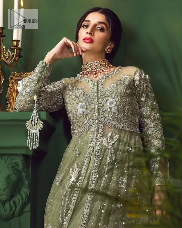 Experience the joy of a wedding in dreamy ensembles. Bringing old-world charm into your festive ensembles, it is a front open scalloped maxi intricately embellished with fine silver embroidery, crystals, tilla, dabka, kora and sequin. The full sleeves of the maxi make it an expression of timeless elegance. In addition to this, the V shape neckline makes this masterpiece unique and priceless. Paired with a long border embellished scalloped dupatta it all comes together to create a luxuriously chic look. The dupatta is also embellished with tiny floral motifs and sequins spray. Complete this party wear with a simple lehenga in the same colour to balance the overall look of the outfit.