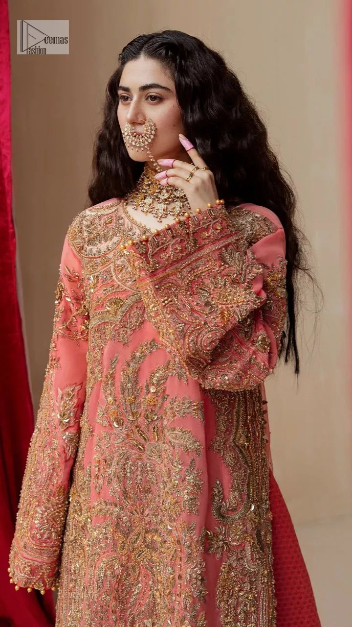 It's an aesthetic kinda mood. The long shirt in the wondrous peach colour is composed of ethnic handworked details and gleaming embellishments rendered artistically on a Jamawar canvas. The long shirt is layered with embroidered details with an enhanced V neckline and borders. The beautiful shirt is prominent with tilla, dabka, kora, Kundan and Zardozi in gold colour. Further, the intricate floral patterns on full sleeves make this outfit crazier. Complementing the shirt with gharara with elaborated borders depicts a perfect contemporary vibe.