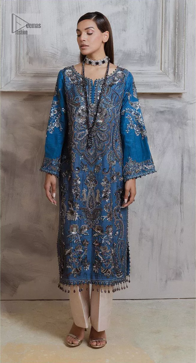 Dress up in this finest two-piece aesthetic party wear. A beautiful shirt in a cadet blue colour is a perfect choice to pair with trousers. The shirt is emblazoned with embroidery, threads, and floral designs. Hand-crafted details of tilla, dabka, Kora and Zardozi make this shirt a ravishing masterpiece. The round neckline is also decorated with attractive embroidery Furter, and the floral patterns on the sleeves give a handsome touch to the following shirt. It is systemized with plain ivory trousers to make a perfect combination which is a perfect choice.