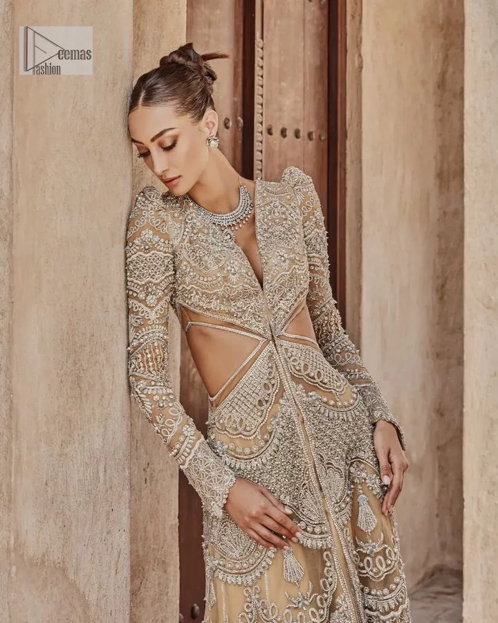 Bold, edgy, and wrapped in glamour. A sumptuous palette of gold with silver delicate embroidery, signature handcrafted embellishment includes tilla, dabka, kora, Kundan, Zardozi and crystals. Take your look to the next level with this golden front open gown which has V shape neckline and full sleeves. The floral patterns on the following gown just steal everyone's heart on your big day. It is paired up with a lehenga to enhance the beauty of this nikah outfit. Complete this article with a dupatta framed with four-sided embellished borders and sequins sprayed all over to wrap you in a bold outfit.