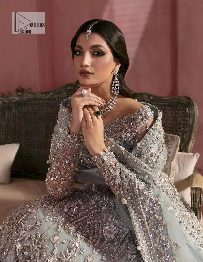 A timelessly classic and hot Nikah wear. DeemasFashion presents the flared maxi in grey colour which is heavily adorned with silver embroidery which is prominent with tilla, dabka, Kora, Kundan and the details of crystals. The boat shape neckline gives a super glamorous touch to the outfit. in addition to this, the floral patterns on full sleeves make this article lovely and romantic. A perfect outfit for an everlasting majestic look is paired up with a dupatta in the same colour framed with four-sided embellished borders and tiny floral motifs all over to give it a perfect royal look.