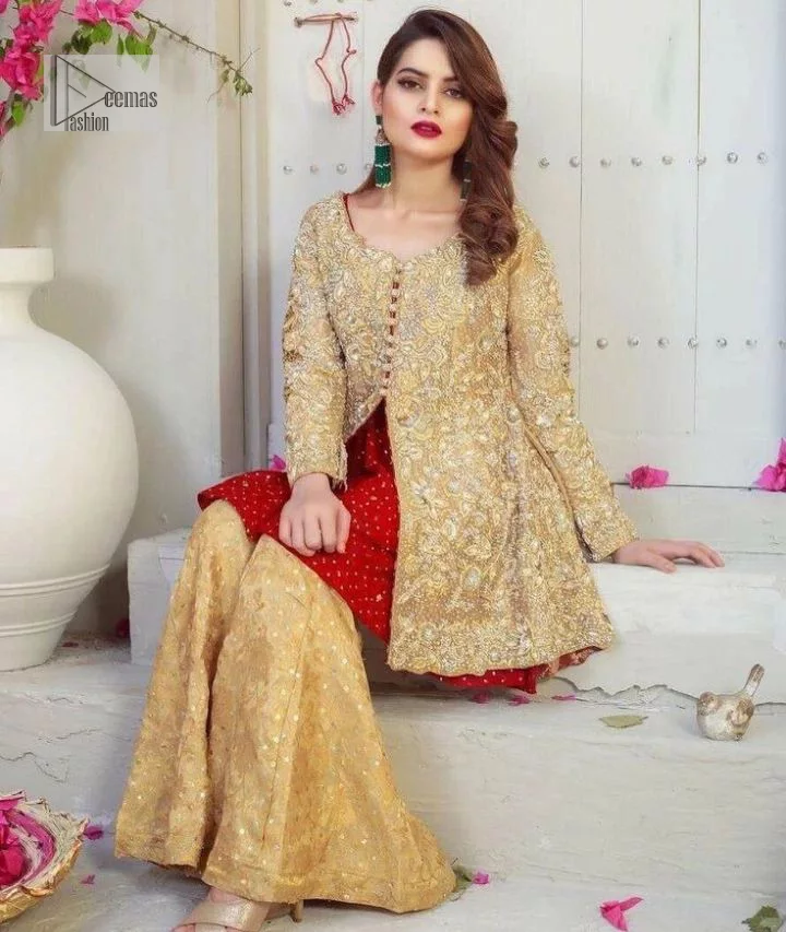 Clean, modern and timeless. The beautiful front-open short shirt in a light golden colour is adorned with embellishments of silver embroidery. It is enhanced with tilla, dabka, kora, Kundan and the real magic of Zardozi. The round neckline makes this outfit unique and lovely. Further, the floral patterns on full sleeves also add super beauty to the outfit. The inner of the short shirt has a red frock combination that gives an aesthetic look. Complete this article with trousers in the same colour as a short shirt just to balance the royal look.   