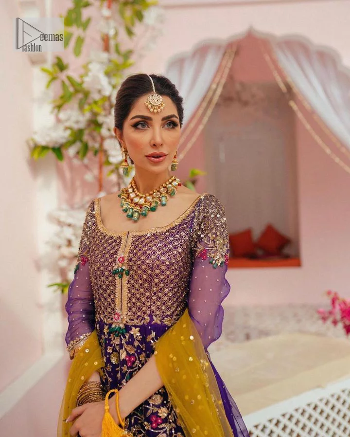Slay your mehndi looks with signature statement pieces. This stunning plum frock is gracefully emblazoned with tilla, dabka, kora, Kundan, Zardozi and crystal details and graceful multiple-colour embroidery work giving you a breathtaking dreamy appearance at the wedding. The floral motifs on the three-quarter sleeves add grace to the outfit. Further, the round neckline has fine details. It is paired up with a lehenga in the same colour having prominent borders just to prominent you on your Mehndi day. Complete this mehndi outfit with a dupatta with sparkling sequins all over to slay your look.