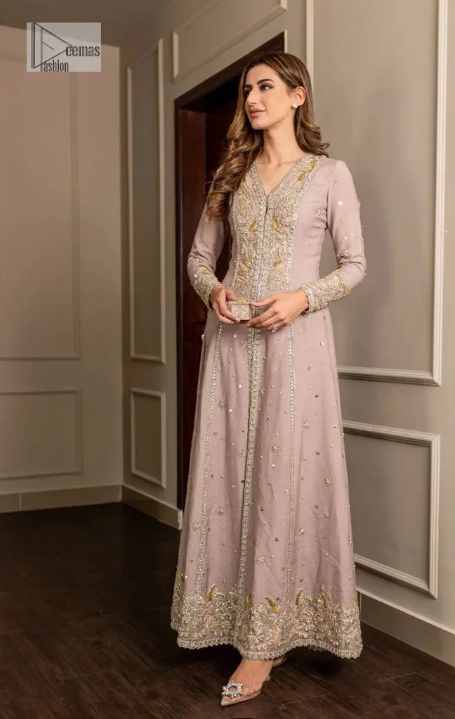 Feel the magic of the party in this splendid article! The ideal front open gown in tea rose colour is heavily hand embellished with floral branches and botanical motifs. It has an embroidered border on the front and back. The V shape neckline is adorned with silver and golden embroidery. It is further prominent with tilla,dabka, kora, Kundan, crystals, stones and the intricate detailing of Zardozi to make this masterpiece lovely and charming. Further, the full sleeves are decorated with tiny floral motifs and sequins spray. It is paired with trousers that complete the party wear look.