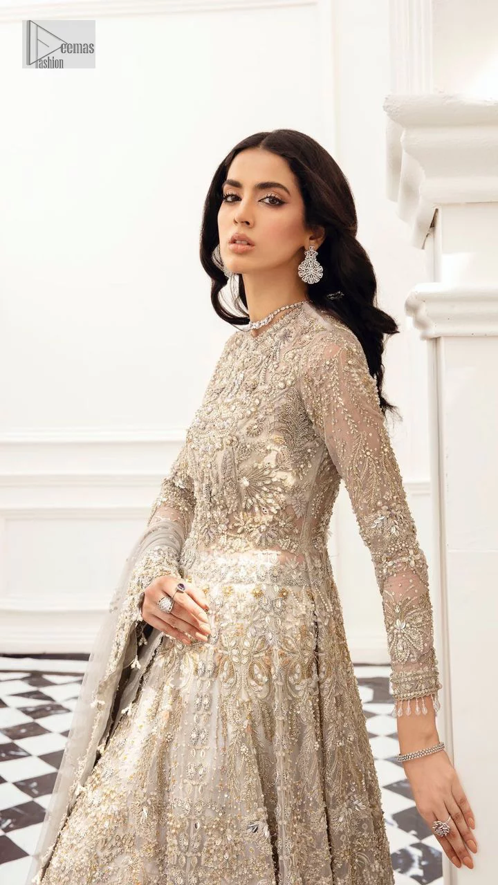 Bright nikah outfits are a constant ongoing trend! Take your look to the next level with this ivory scalloped maxi having silver and golden embellishment frames. The following maxi is highlighted with tilla, dabka, kora, Kundan, and the beautiful details of Zardozi. The jewel neckline reveals layers of priority. Furthermore, the floral patterns on full sleeves look like a complete diva.  The beautiful dupatta is framed with a floral scalloped border on all sides to give a vibrant and soft look.