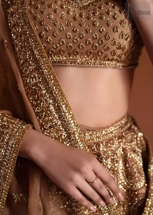 A striking look at the lower lehenga hemline, dominated by a heavy, sculptural antique border rich with layered zardozi, stones,