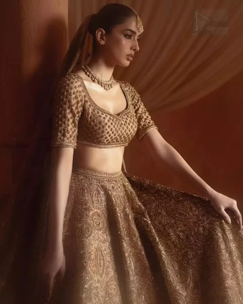 Three-quarter angled view of bronze bridal lehenga and organza dupatta.