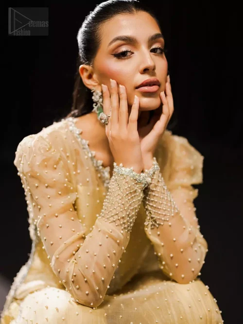Round notched neckline with silver embroidery and pearl details on light yellow shirt.